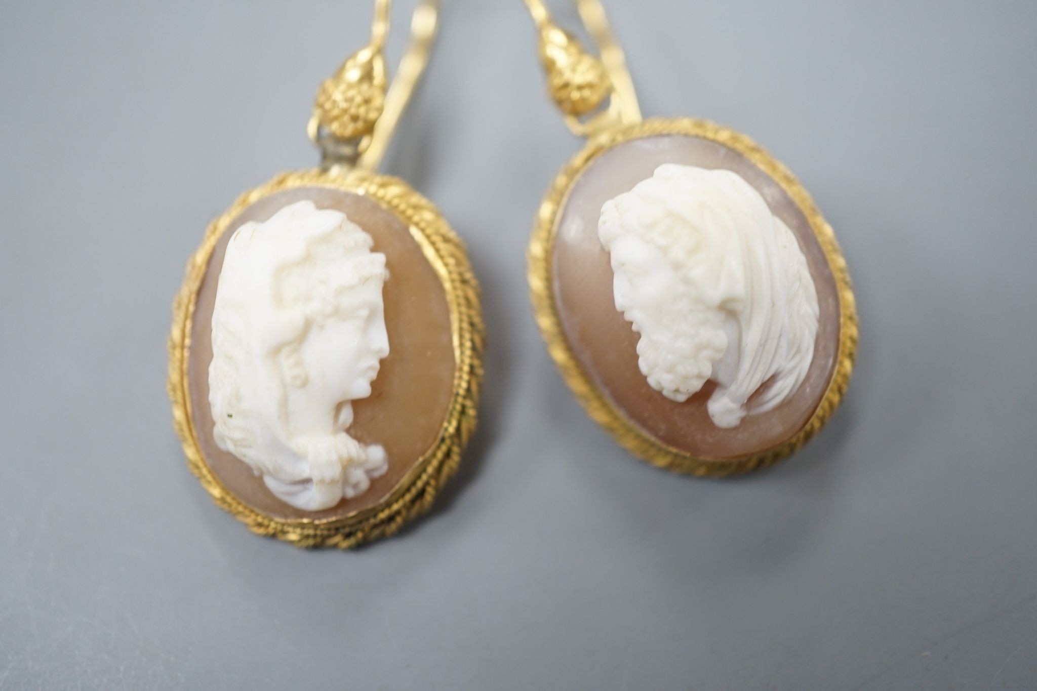A pair of early 20th century yellow metal and oval cameo shell earrings, carved with a lady to sinister and a gentleman to dexter, overall 40mm, gross 6.2 grams.